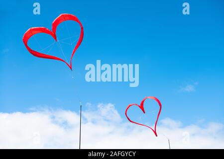Due rosso a forma di cuore ad aquiloni su un cielo blu con nuvole bianche Foto Stock