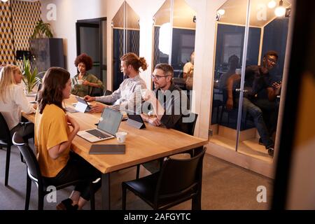 Creative colleghi seduti ad un tavolo di socializzare nel loro ufficio mensa Foto Stock