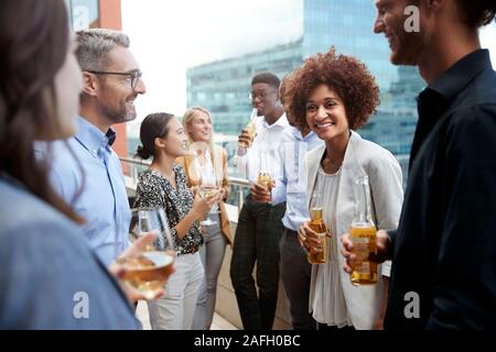 Colleghi di lavoro a parlare e a bere insieme su un balcone in città dopo il lavoro Foto Stock