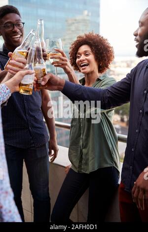 Sorridente azienda creativa ai colleghi di bere dopo i lavori di sollevamento vetri per fare un brindisi, verticale Foto Stock