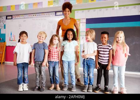 Ritratto di scuola elementare gli allievi in piedi in aula con docente femminile Foto Stock