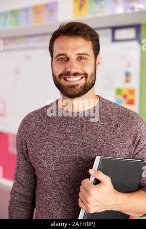 Ritratto maschile di insegnante di scuola elementare in piedi in aula Foto Stock