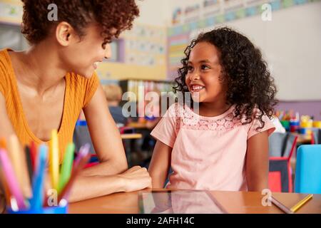 Insegnante di scuola elementare e pupilla femmina disegno usando digitale compressa in aula Foto Stock