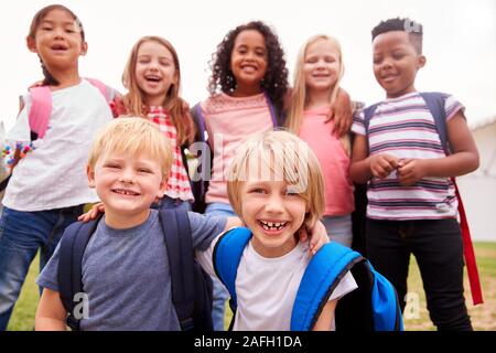 Ritratto di eccitato Scuola Elementare alunni sul campo da gioco in pausa Foto Stock