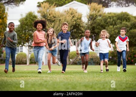 Eccitato Scuola Elementare gli alunni che attraversano il campo in corrispondenza del tempo di rottura Foto Stock