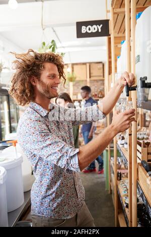 L'uomo recipiente di riempimento con la polvere di lavastoviglie in plastica libera Fruttivendolo Foto Stock