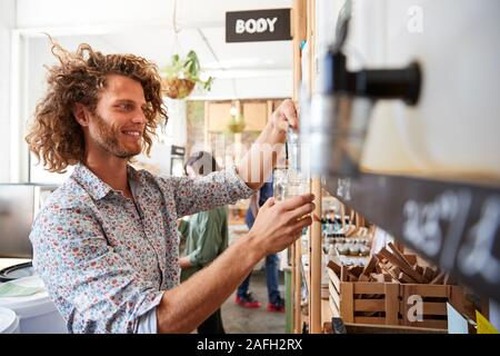 L'uomo recipiente di riempimento con la polvere di lavastoviglie in plastica libera Fruttivendolo Foto Stock