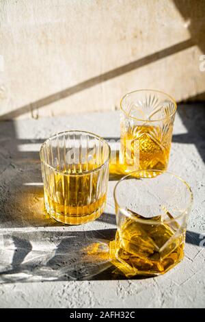 Whiskey in bicchieri sul tavolo in condizioni di luce solare intensa, giallo drink con bella illuminazione sun Foto Stock