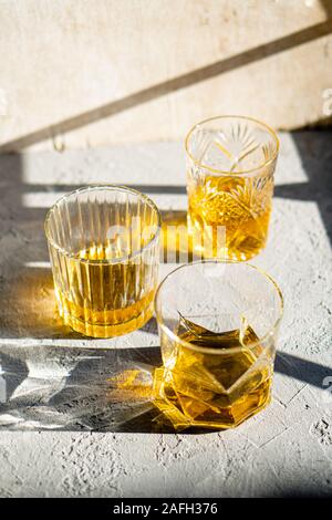 Whiskey in bicchieri sul tavolo in condizioni di luce solare intensa, giallo drink con bella illuminazione sun Foto Stock