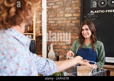 Il cliente paga per lo shopping al checkout della plastica sostenibile libera Fruttivendolo Foto Stock