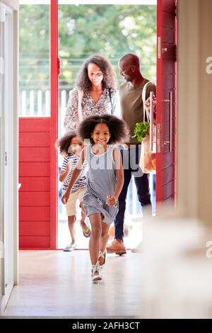 Famiglia tornando a casa dal viaggio di shopping utilizza plastica libera drogheria sacchetti di apertura della porta anteriore Foto Stock