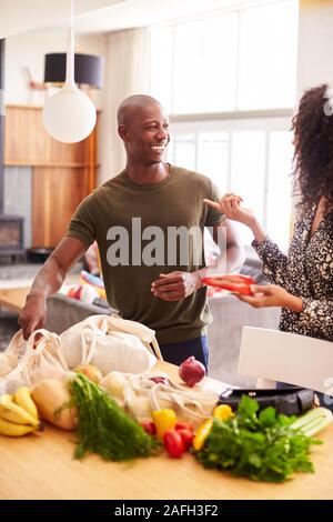 Giovane tornando a casa dal viaggio di shopping disimballaggio libera di plastica Sacchi di negozi di generi alimentari Foto Stock