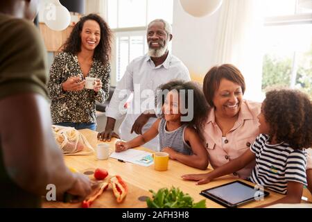 Nonni seduta a tavola con i nipoti giocare come famiglia prepara pasti Foto Stock