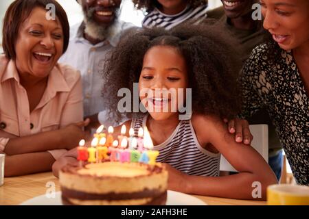 Famiglia Multi-Generation celebrando nipoti compleanno a casa con torta e candele Foto Stock