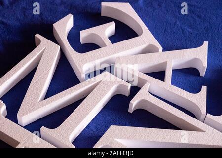 Lettere bianche tagliate fuori della schiuma senza verniciatura su uno sfondo blu. vuoto per la decorazione, rendendo il logo Foto Stock
