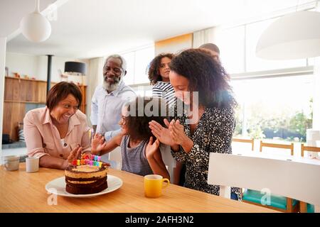 Famiglia Multi-Generation celebrando nipoti compleanno a casa con torta e candele Foto Stock