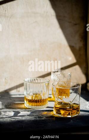 Whiskey in bicchieri sul tavolo in condizioni di luce solare intensa, giallo drink con bella illuminazione sun Foto Stock