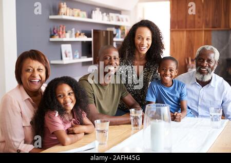 Ritratto di famiglia Multi-Generation seduti attorno al tavolo di gioco a casa godendo di pasto insieme Foto Stock