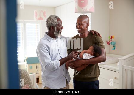 Orgogliosi di Nonno con figlio adulto coccole Baby nipote in vivaio a casa Foto Stock