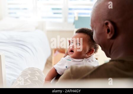 Padre orgoglioso delle coccole figlio neonato nel nido a casa Foto Stock