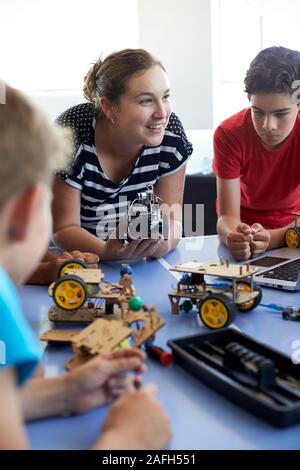 Gli studenti Nel dopo scuola di computer di codifica edificio di classe e imparare a programmare un veicolo robot Foto Stock