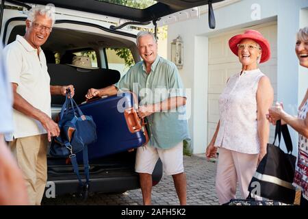 Gruppo di amici Senior di carico dei bagagli nel tronco della vettura in procinto di partire per le vacanze Foto Stock