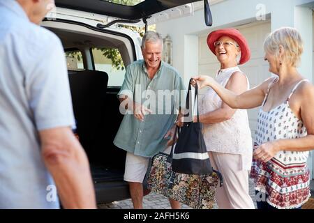 Gruppo di amici Senior di carico dei bagagli nel tronco della vettura in procinto di partire per le vacanze Foto Stock
