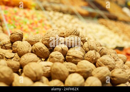 In tonalità calde sullo sfondo di un mucchio di noci frutta secca stand nel mercato degli agricoltori o al supermercato, spazio di copia Foto Stock