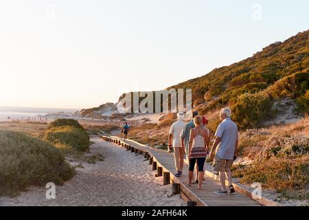 Gruppo di amici Senior camminare lungo la passeggiata a mare in spiaggia in estate vacanze di gruppo Foto Stock