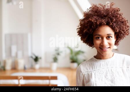 Ritratto di sorridente giovane donna in Appartamento Loft Foto Stock