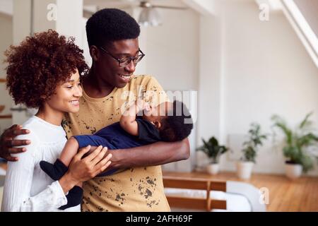 Amare i genitori tenendo neonato a casa In Appartamento Loft Foto Stock