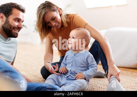 I genitori seduti sul pavimento a casa a giocare con il bambino figlio Foto Stock