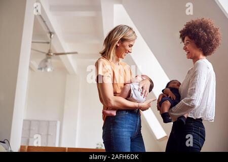 Due madri incontro tenendo i neonati a casa In Appartamento Loft Foto Stock