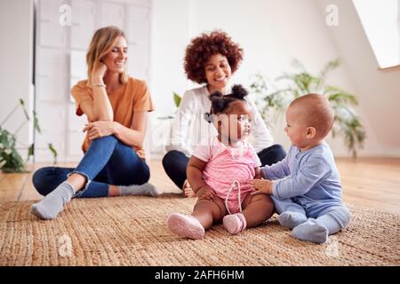 Due madri incontro per data di gioco con i bambini a casa In Appartamento Loft Foto Stock