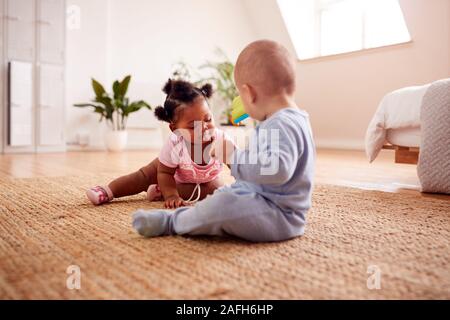 Baby Ragazzo e ragazza che gioca con i giocattoli sul tappeto a casa insieme Foto Stock