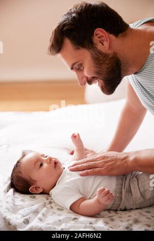 Padre amorevole che giace con Neonato su letto di casa in Appartamento Loft Foto Stock