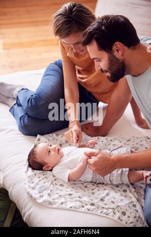 Amare i genitori con bambino neonato sdraiato sul letto di casa in Appartamento Loft Foto Stock