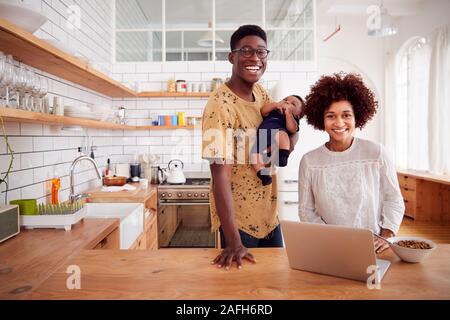 Ritratto di famiglia occupato in cucina per la prima colazione con il padre la cura per il bambino figlio Foto Stock