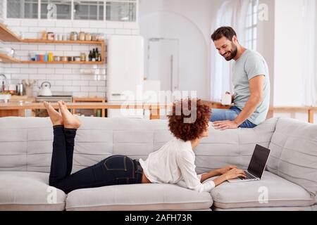 Giovane rilassante sul divano di casa Guardando insieme per Laptop Foto Stock