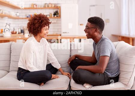 Coppia giovane rilassante sul divano di casa a parlare insieme Foto Stock