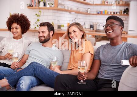 Gruppo di amici seduti sul divano e guardare film a casa mentre si beve vino Foto Stock