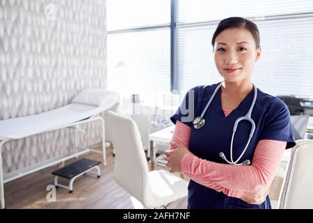 Ritratto Di Donna sorridente medico con stetoscopio in piedi da scrivania in ufficio Foto Stock