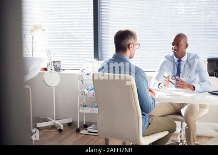 Maschio maturo paziente in consultazione con il medico in ufficio Foto Stock