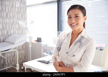 Ritratto Di Donna sorridente medico con stetoscopio in piedi da scrivania in ufficio Foto Stock
