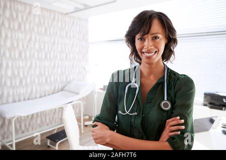 Ritratto Di Donna sorridente medico con stetoscopio in piedi da scrivania in ufficio Foto Stock