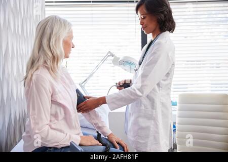 Donna paziente avente la pressione del sangue presa dal medico donna in Office Foto Stock