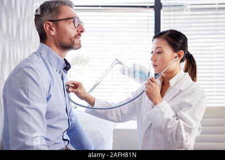 Maschio maturo paziente avente Medical Exam con la donna medico in ufficio Foto Stock