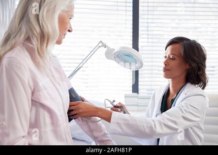 Donna paziente avente la pressione del sangue presa dal medico donna in Office Foto Stock