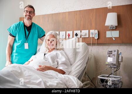 Ritratto di chirurgo visitando femmina matura paziente nel letto di ospedale Foto Stock