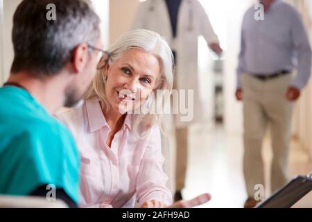 Medico accogliente per Senior paziente femmina essendo ricoverato in ospedale Foto Stock